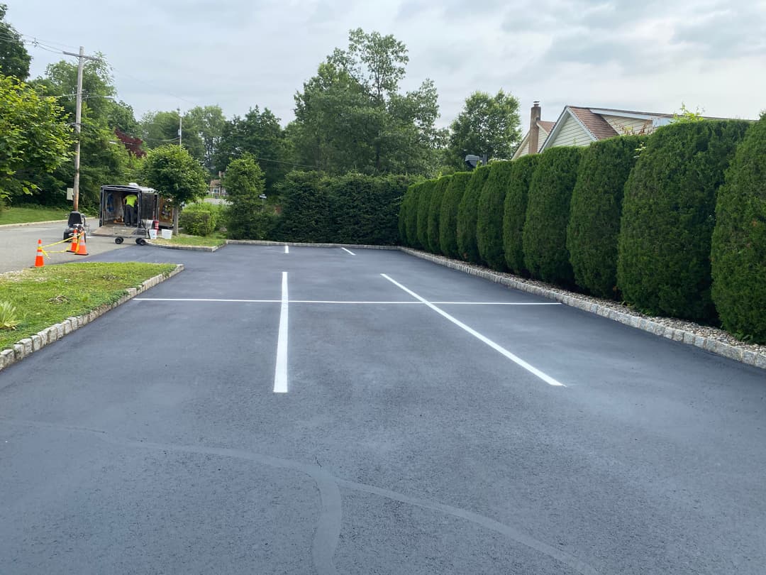 Freshly painted parking lot with clear white stripes and well-maintained hedges.