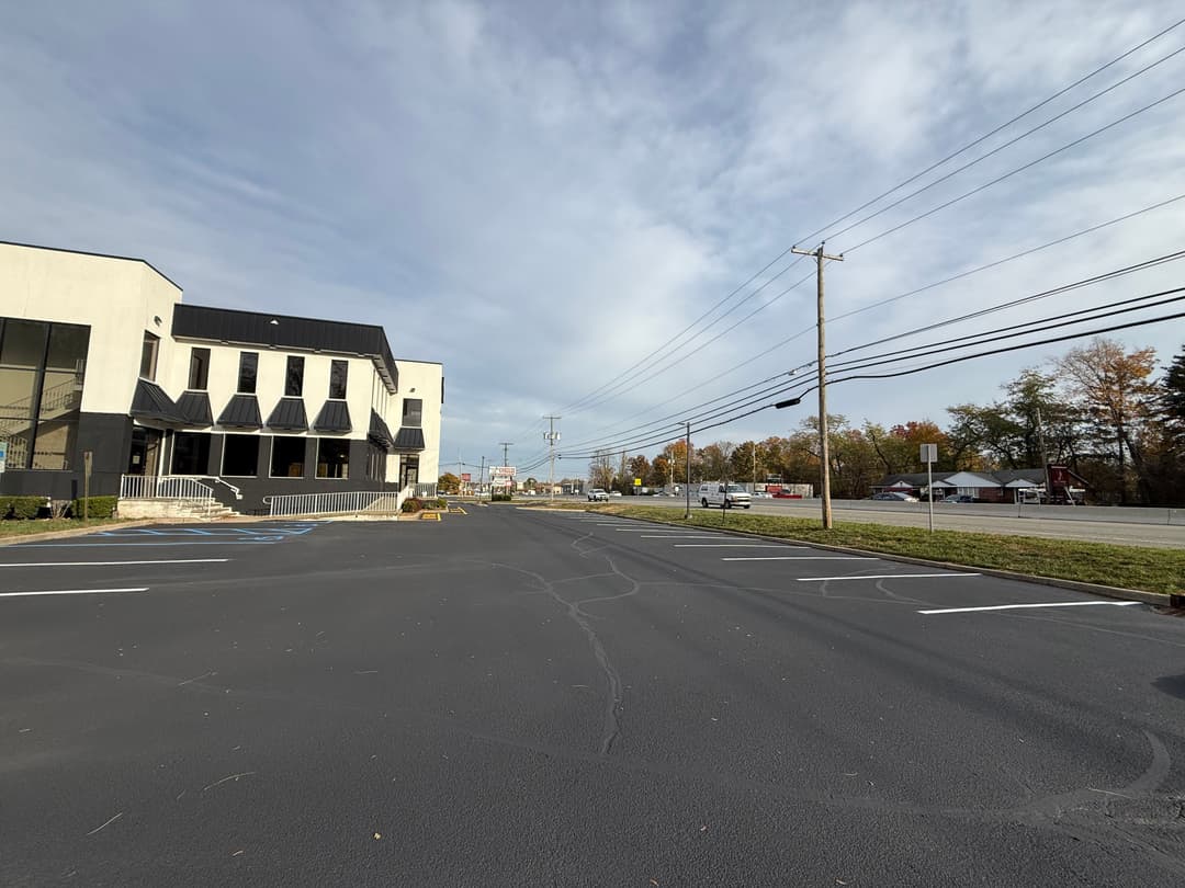 Empty parking lot in front of a modern building with utility poles and power lines.