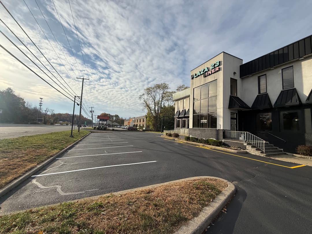 Pizza diner building with large windows and a vacant parking lot on a clear day.