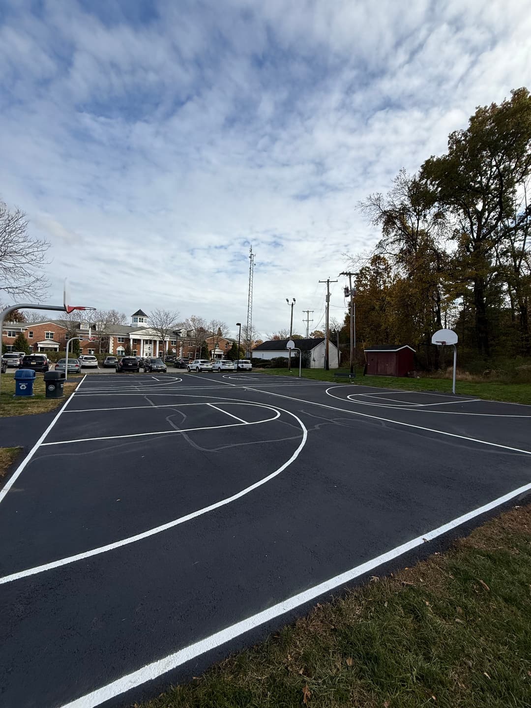 Empty basketball court with clear lines and a view of trees and buildings in the background.