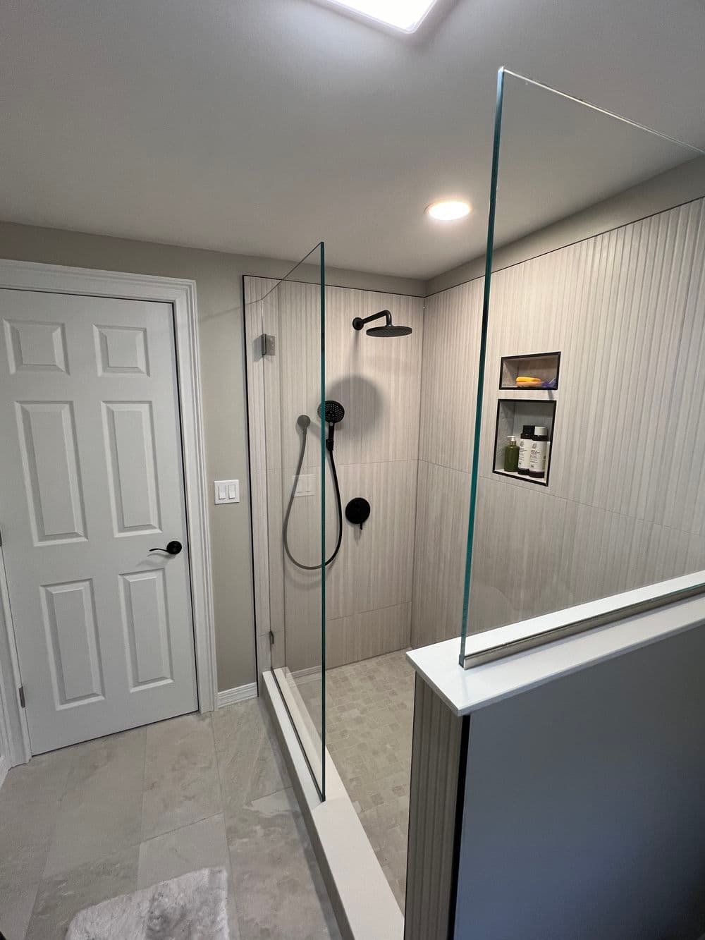 Modern shower with glass enclosure, rain showerhead, and stylish tiled walls in a bright bathroom.
