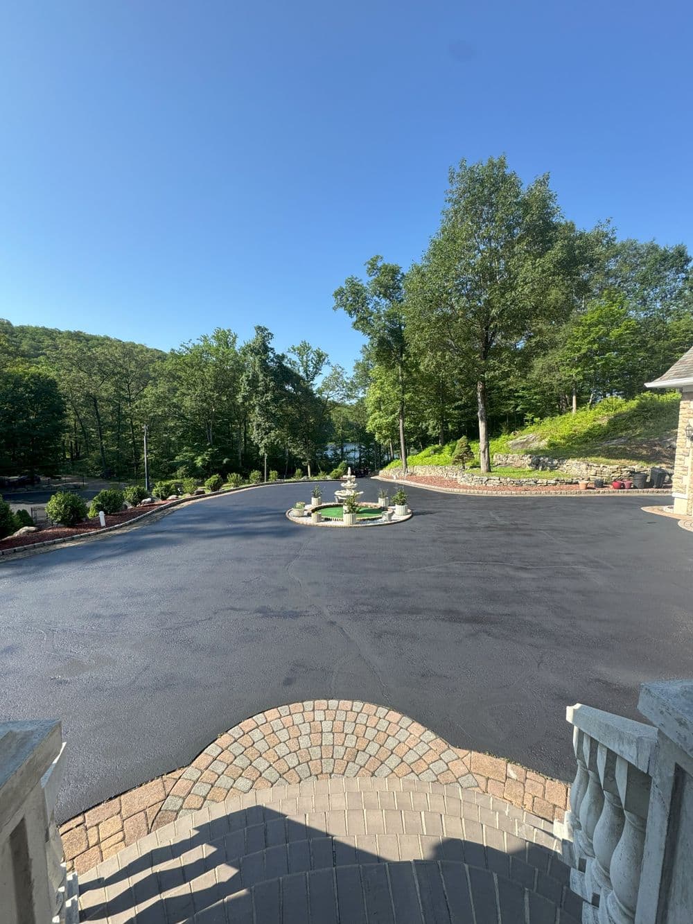 Scenic driveway leading to a house, surrounded by trees and a clear blue sky.