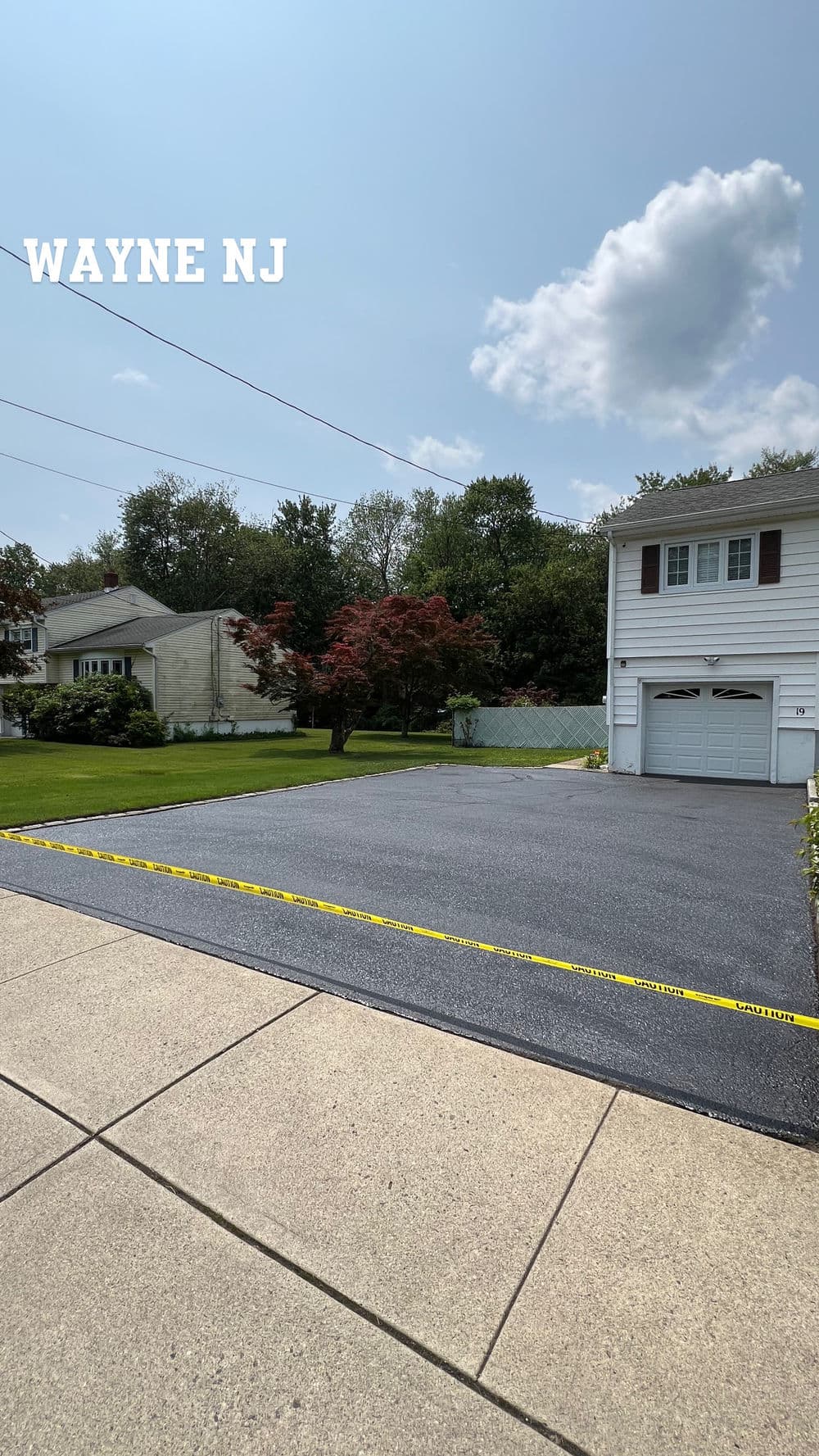Residential driveway in Wayne, NJ, with fresh asphalt and caution tape marking the area.