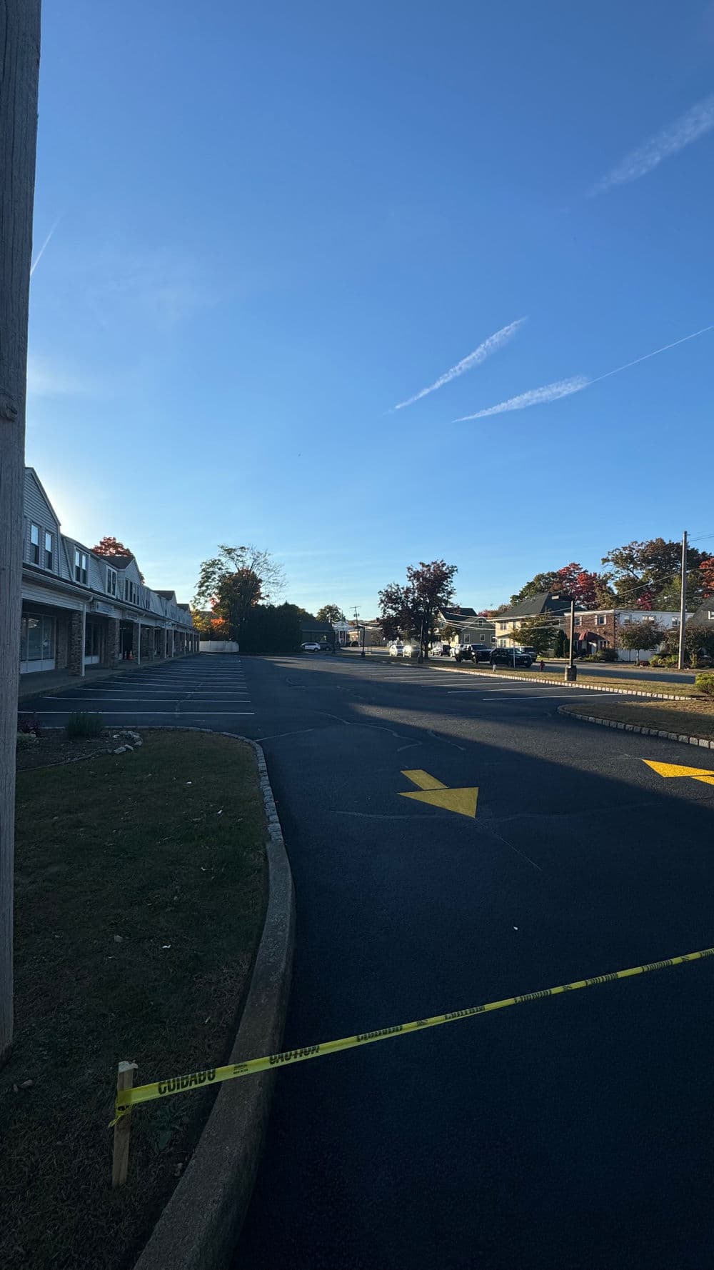 Street view with yellow police tape and clear blue sky, showcasing a quiet neighborhood in Colorado.