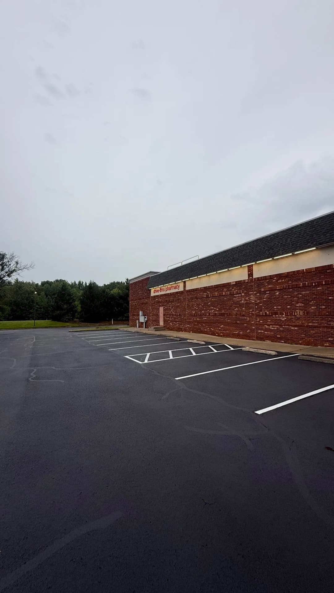 Empty parking lot and brick exterior of a retail establishment under a cloudy sky.